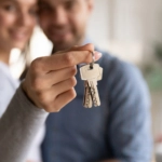 Close up happy young woman hugging man, holding keys